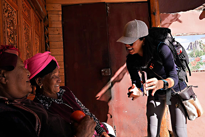 Zhang Mei shows photos on her phone to Mosuo villagers. Photo: Marina Zhang